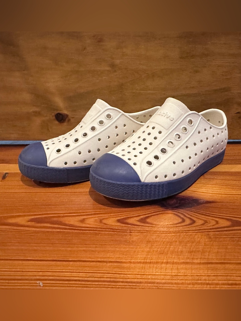 Native Kids’ Slip-On Sneakers in White with Navy Blue Accents